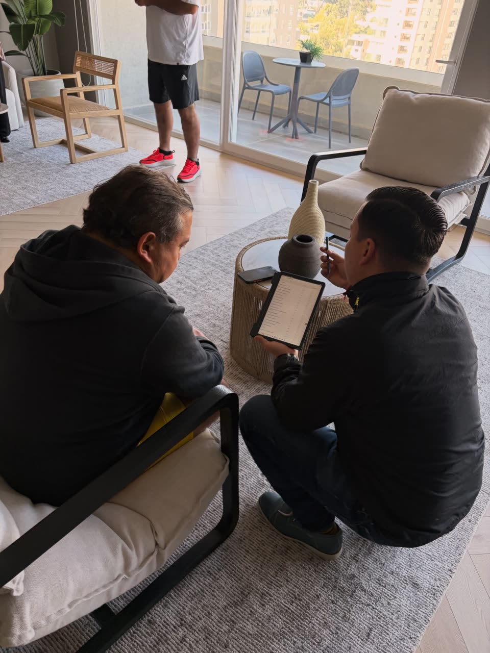 Cristian revisando los detalles de un departamento junto a un cliente, tablet en mano